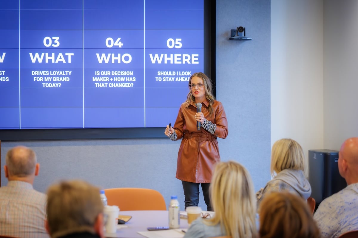 Amanda Schneider presenting and speaking into a microphone in front of an audience at a conference.